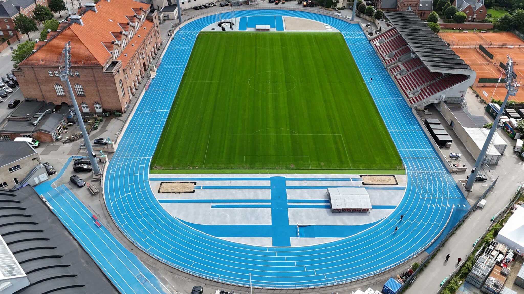 Luftfoto af et sportsstadion med en markant blå løbebane.